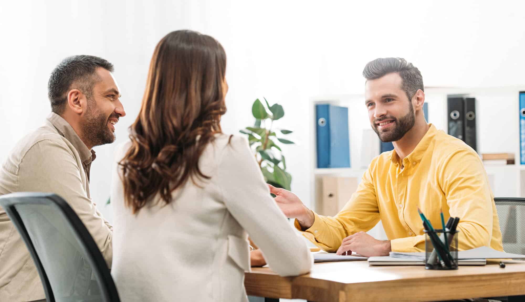 Credit counselor providing financial advice to a young couple in his office.