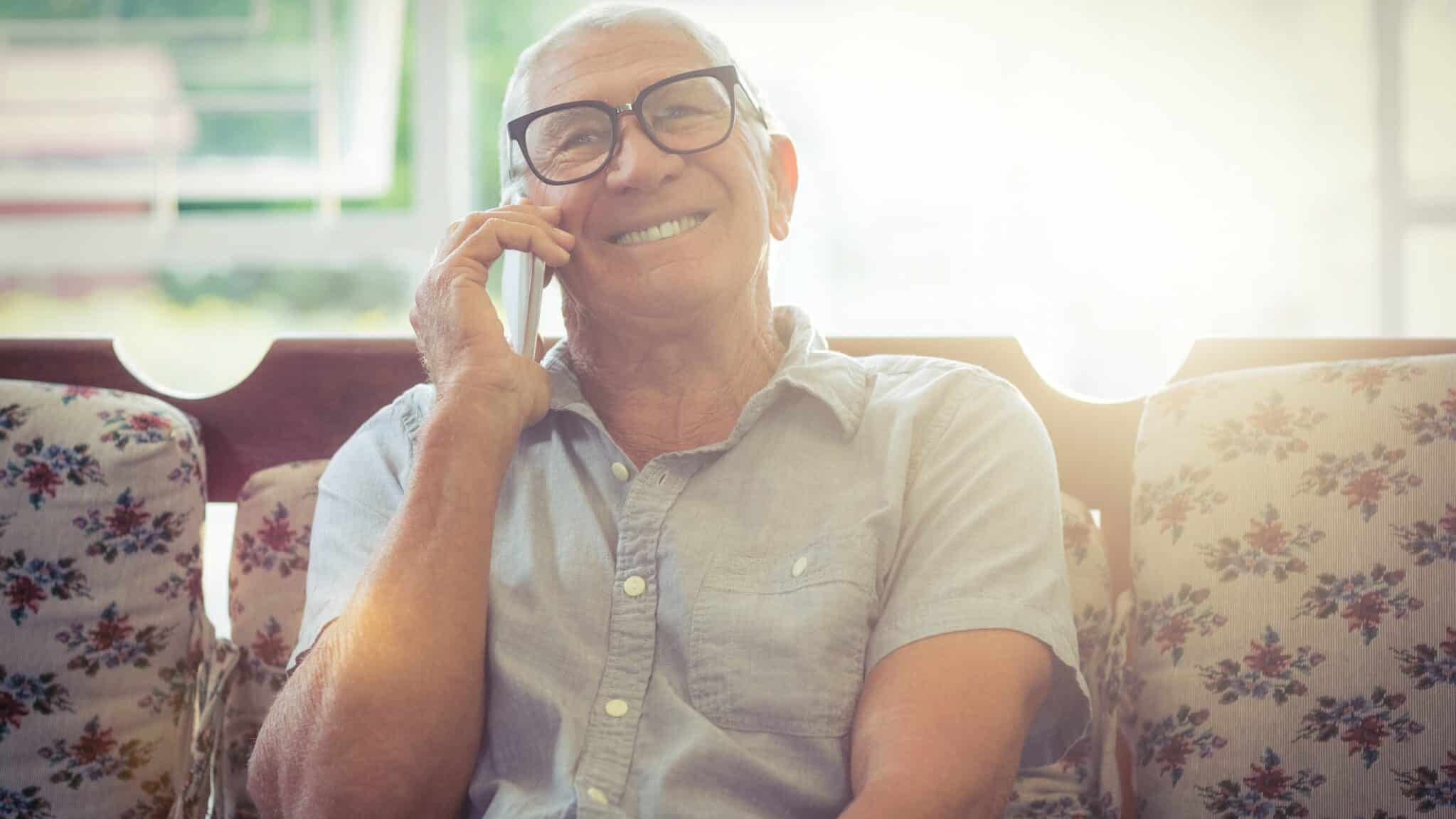 Smiling older adult talking on the phone during a calm conversation at home
