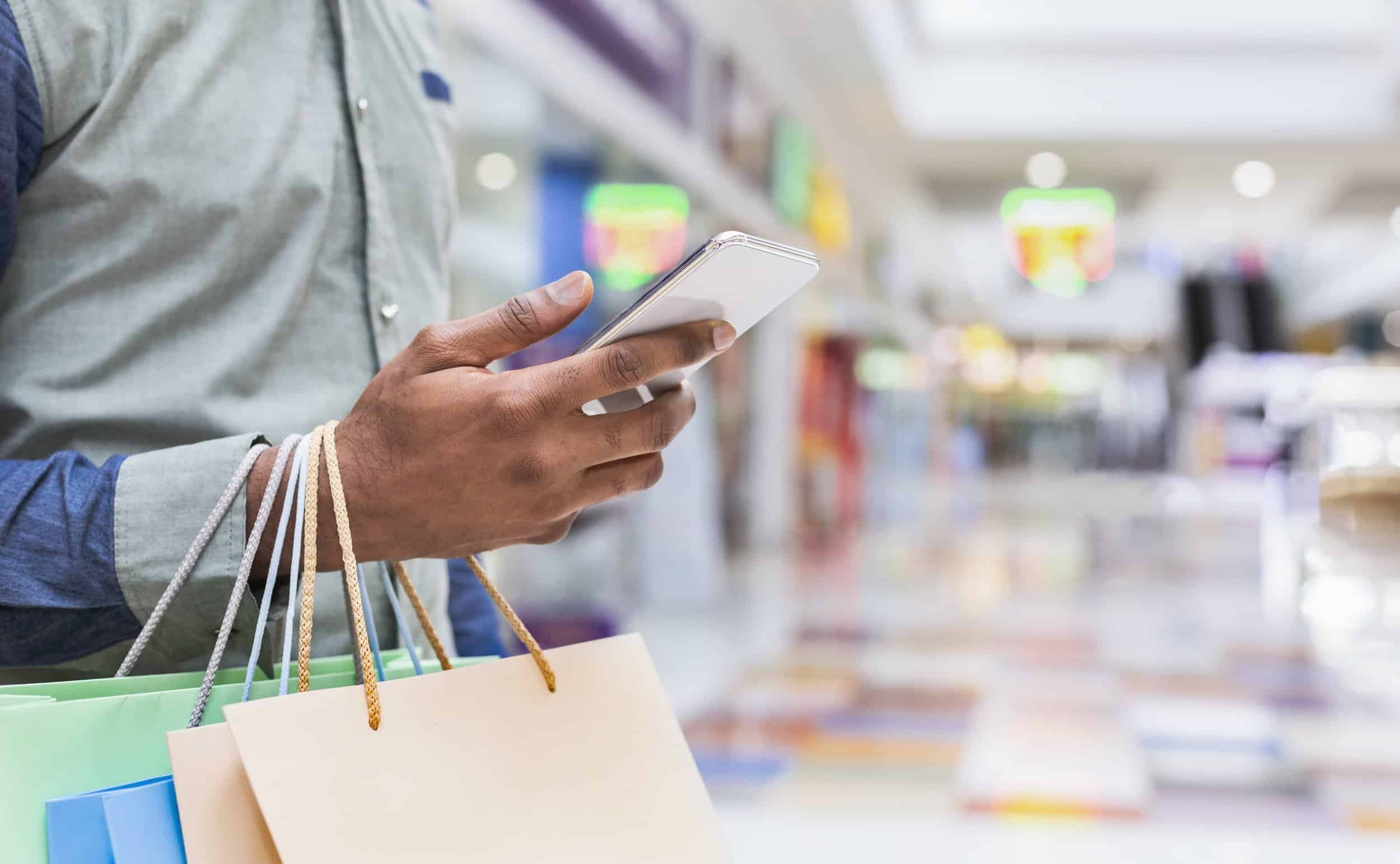 Young man searching new clothes through cellphone online