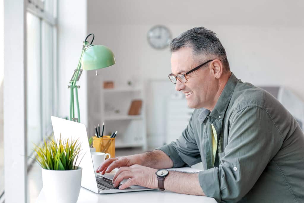Mature man learning on laptop, obtaining certificates through Money Fit's online bankruptcy counseling and debtor education services