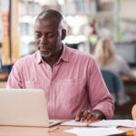 A man sitting at a desk with a laptop and paperwork in front of him.