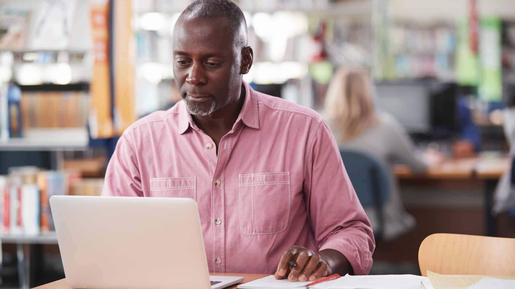 A man sitting at a desk with a laptop and paperwork in front of him.