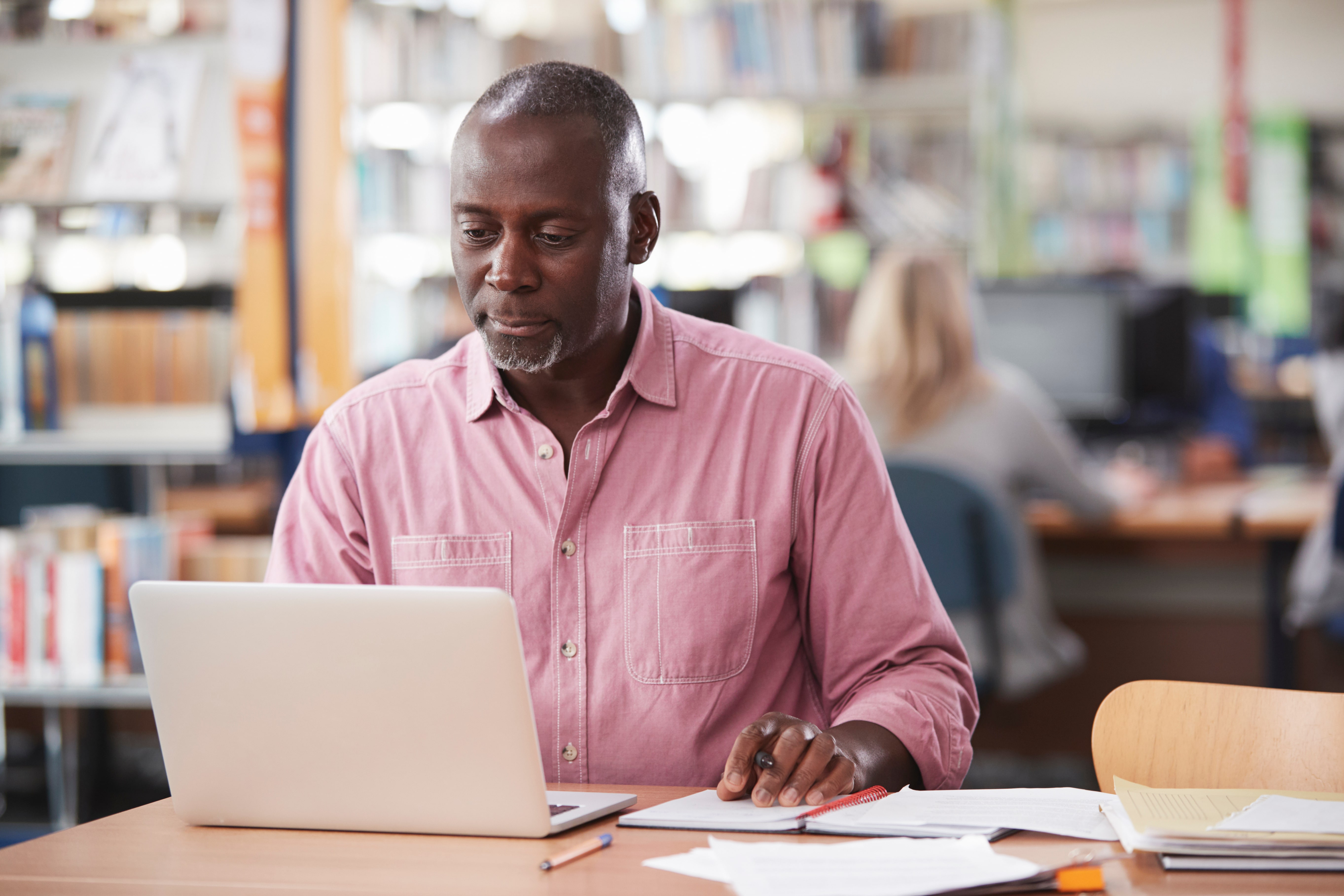 A man sitting at a desk with a laptop and paperwork in front of him.