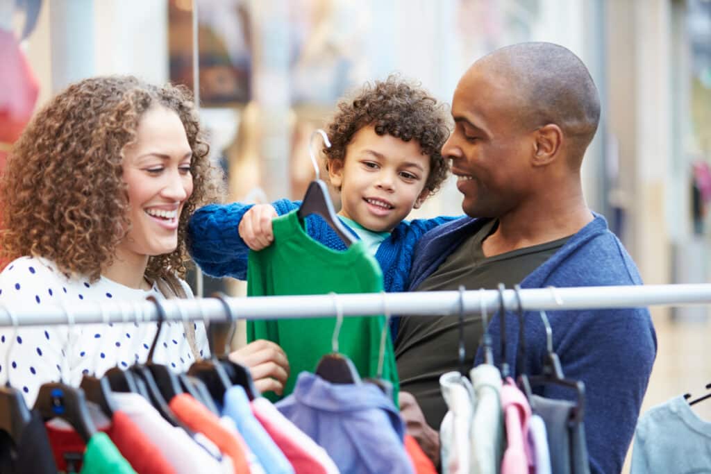 Parents shopping with young child for clothes.