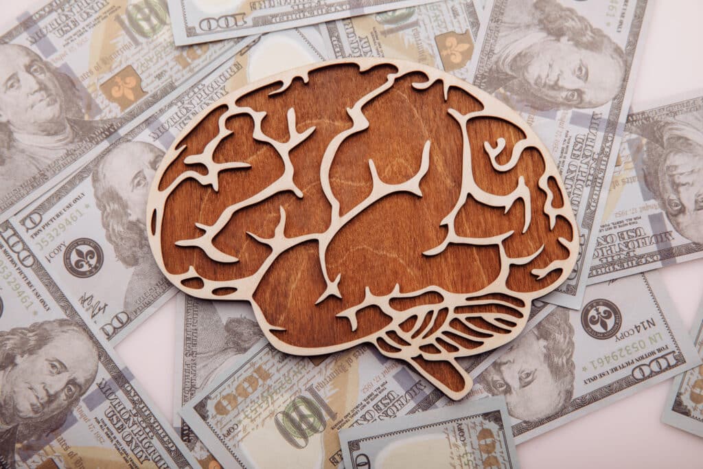 A model of a brain sits atop of spread out US currency