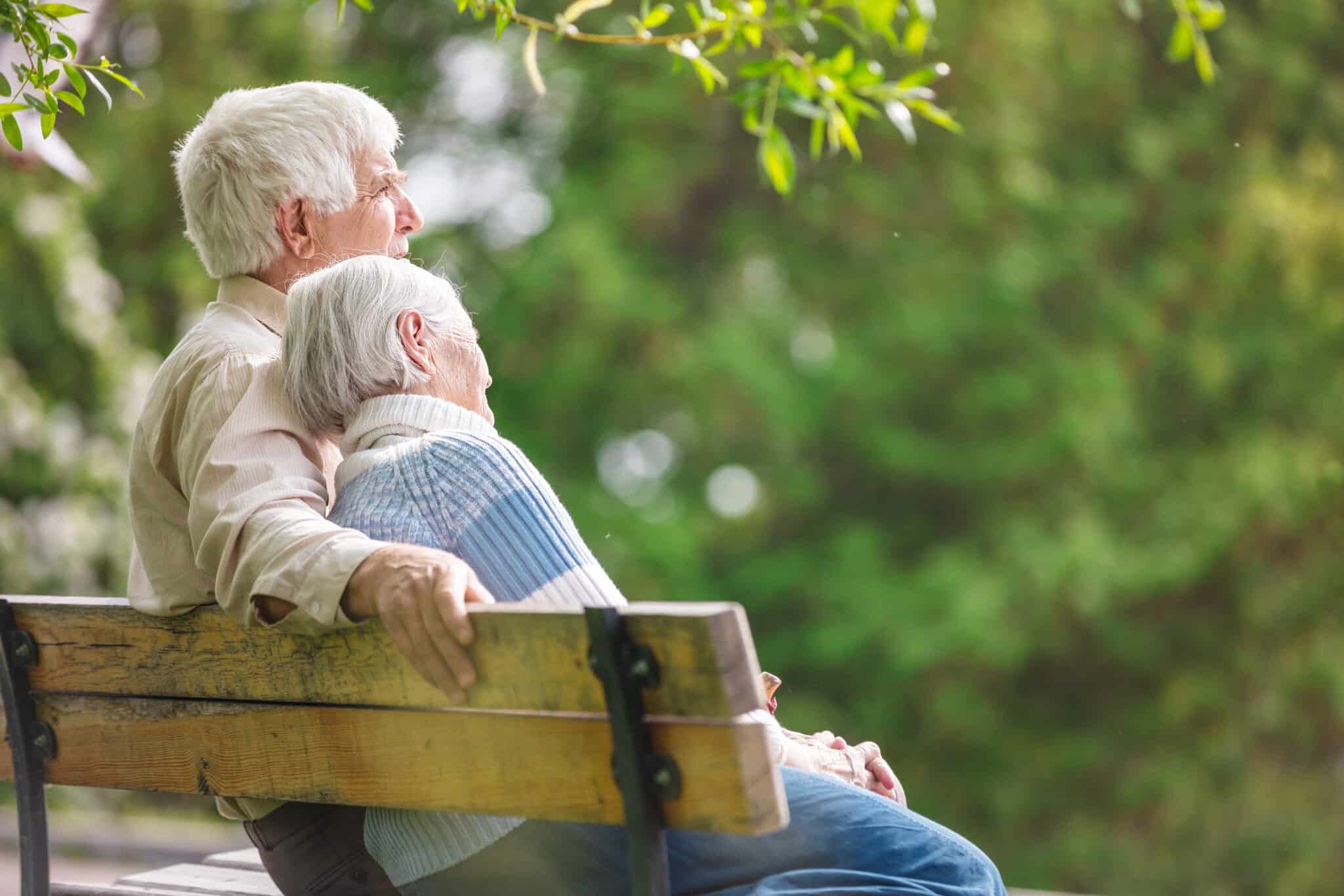 elderly couple resting on a bench in the park