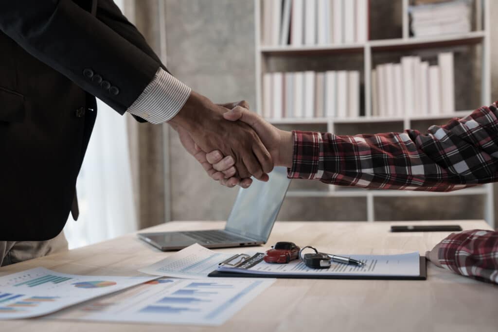 new car loan contract, keys and shaking hands