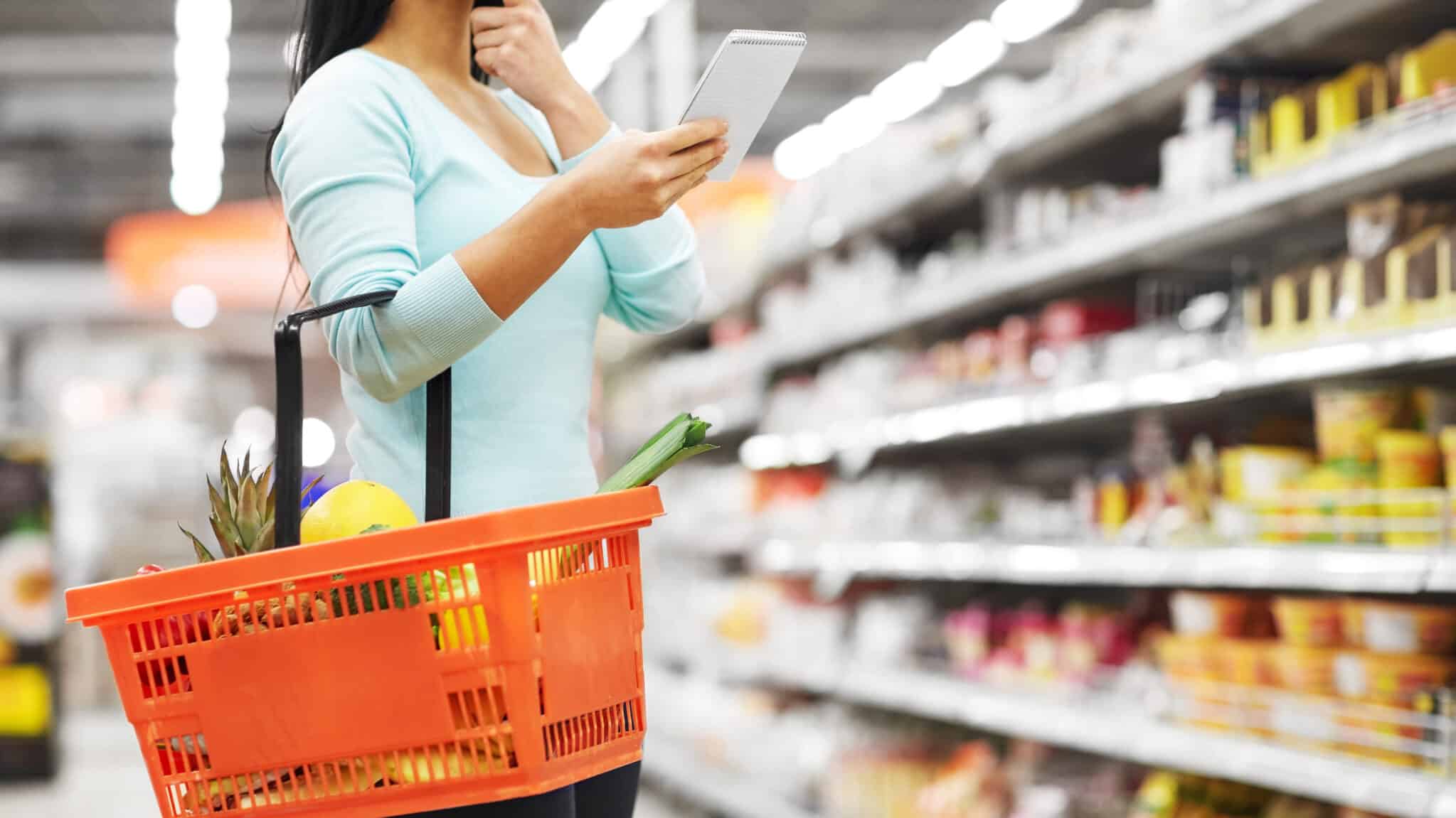 woman shopping in grocery store with list on a tablet
