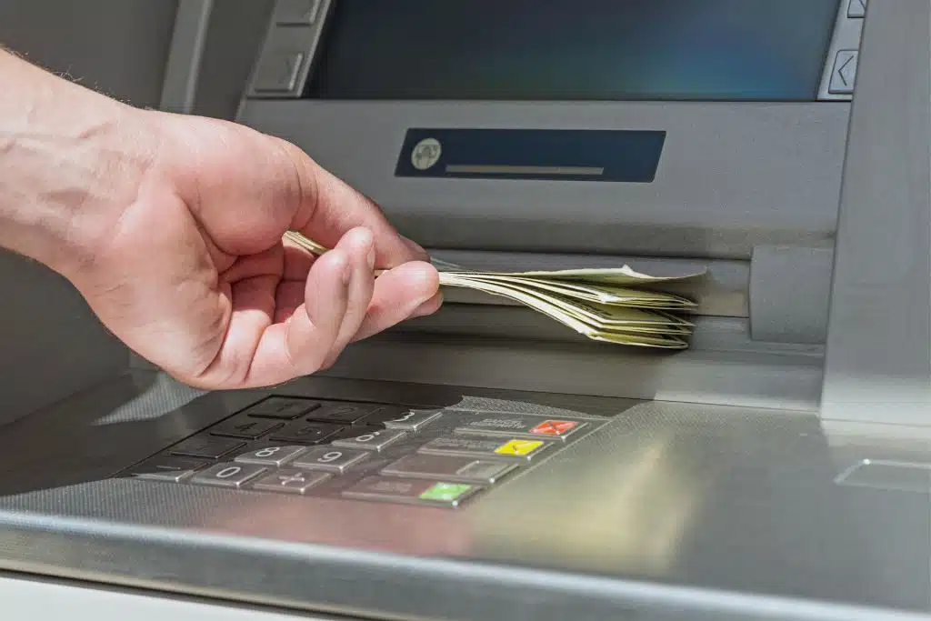 Person using an ATM and securely writing a check