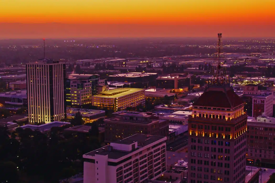 Downtown Fresno skyline at sunset with the Pacific Southwest Building and surrounding city lights.