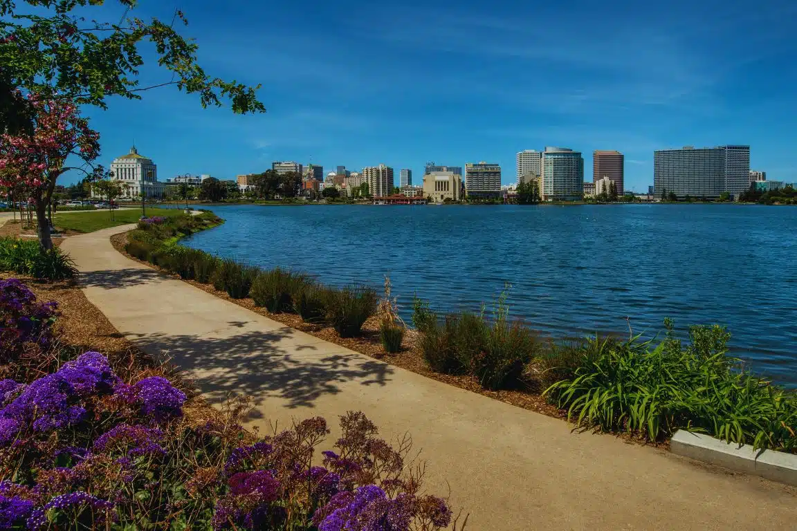 Lake Merritt in Oakland with flowers, a walking path, and downtown skyline in the background.