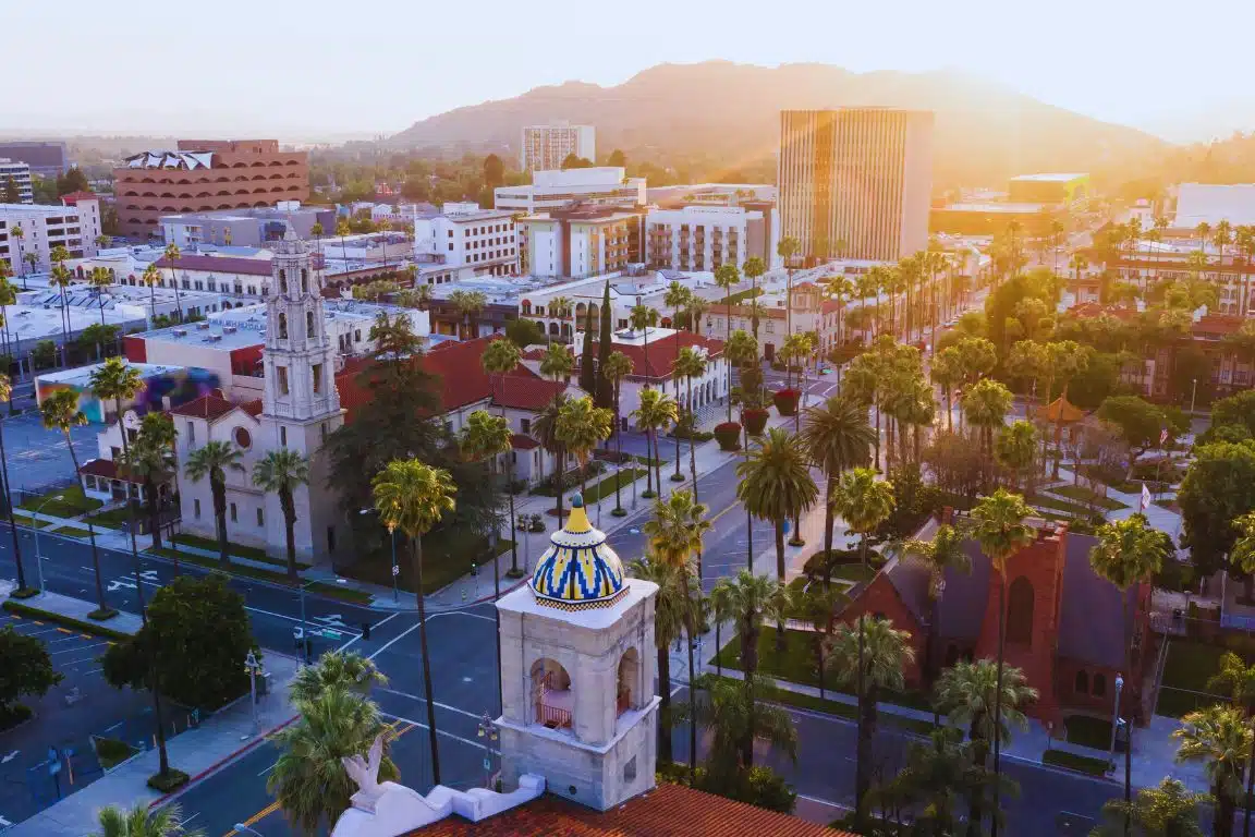 Downtown Riverside with historic Mission Revival architecture, palm-lined streets, and hills at sunset.