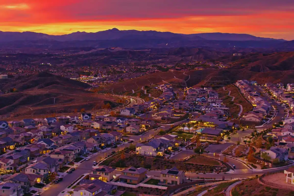 Santa Clarita neighborhoods and winding roads at sunset with rolling hills and mountains in the background.