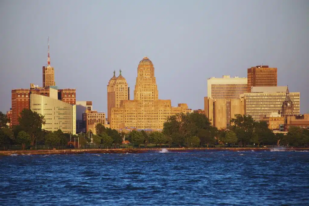 Buffalo skyline from the waterfront with Art Deco City Hall and downtown buildings in warm evening light.