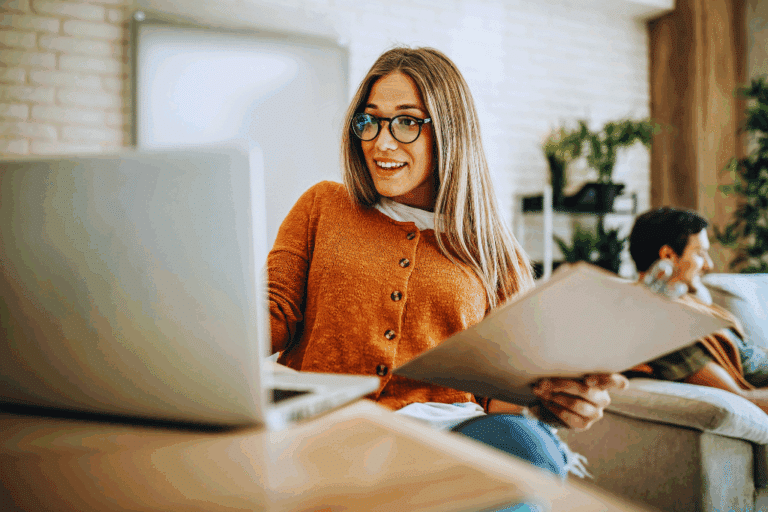 Young woman completing a HUD-approved homebuyer education course on a laptop while reviewing notes at home.