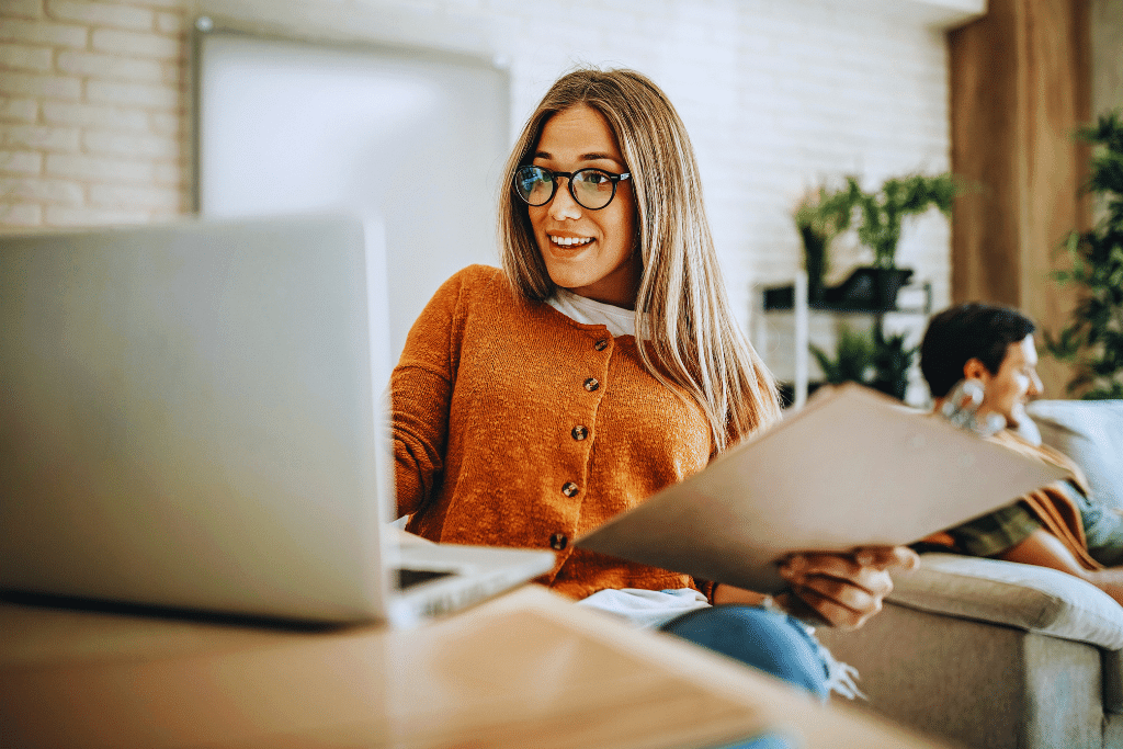 Young woman completing a HUD-approved homebuyer education course on a laptop while reviewing notes at home.