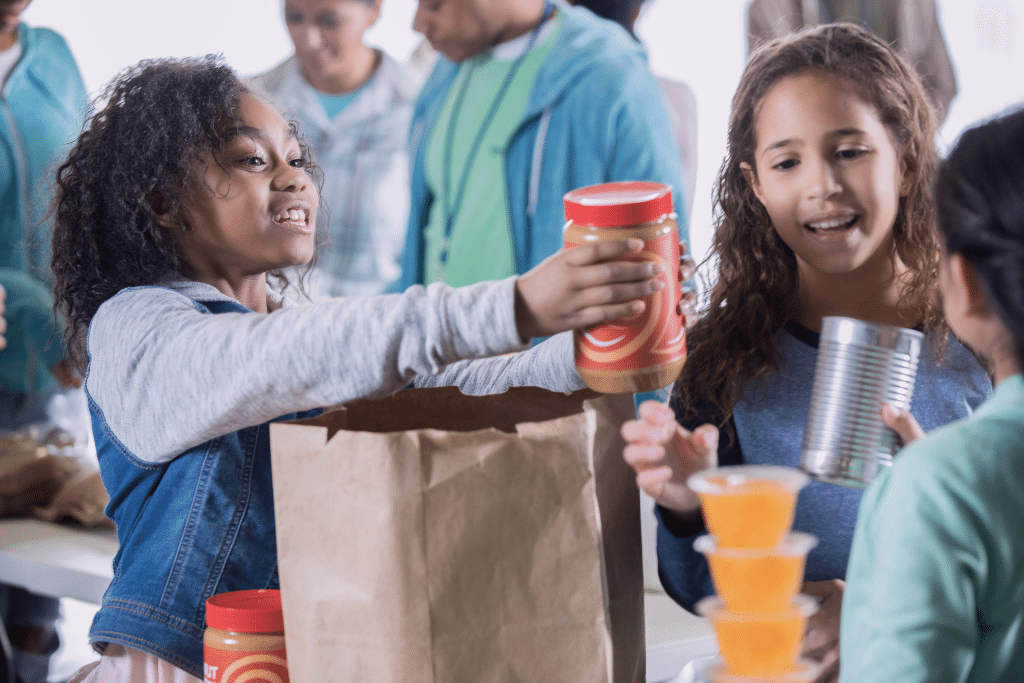 Children volunteering at a community food drive, sharing canned goods and peanut butter with smiles.