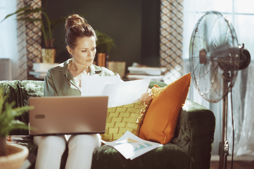 Woman reviewing financial documents with a laptop at home while budgeting and checking expenses