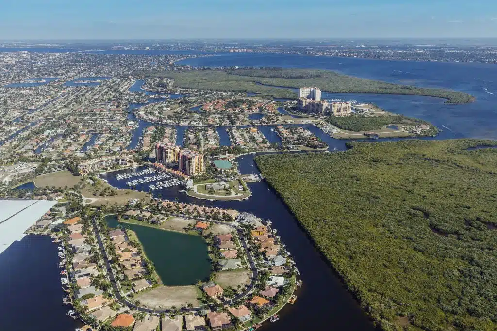 Cape Coral canals at sunset with boats docked, palm trees, and residential homes lining the waterways.