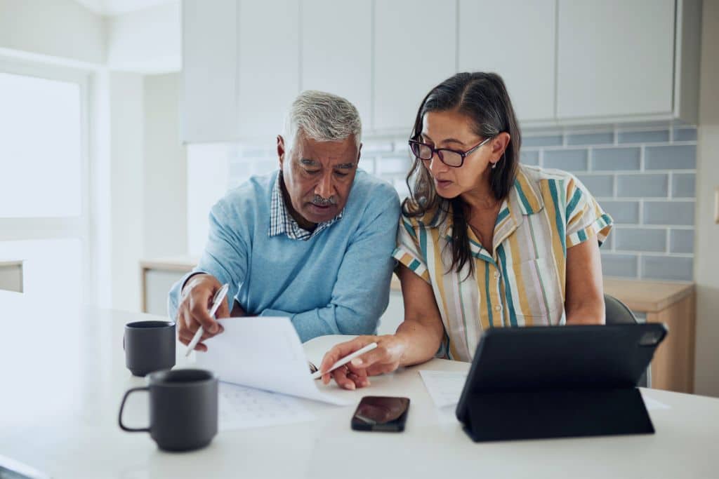 Couple reviewing mortgage paperwork at home with a laptop and documents
