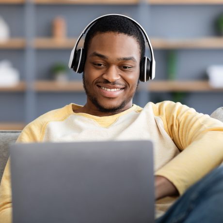 Discover Personal Finance Topics with our Video Library A man watching a video on personal finance on his laptop with a smile, indicating engagement